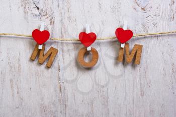 wood letters and heart forming phrase mom on old wooden white  background