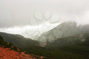Green hills in the mountains, fog, rain. Dramatic sky. Bad weather in mountains