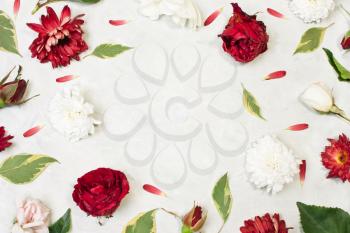 The composition of flowers. Decorations of red roses, buds, green leaves and white chrysanthemums on gray concrete background. View from above, flat