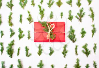 Christmas present in tree leaves. New Year's gift in red wrapping paper with branches of the Christmas tree. Concept christmas holiday