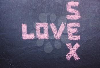 The word love and sex are written with pink chalk on a blackboard