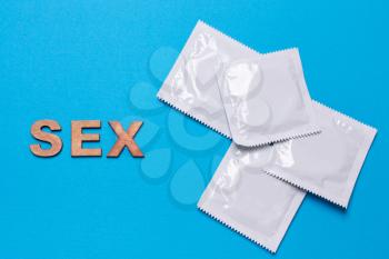 Condom and word sex on a blue background. Flat view, from above. The concept of safe sex