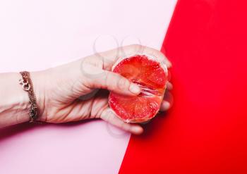 Concept sex, masturbation. Hand, fingers in grapefruit, vagina symbol on a red background