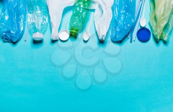 Plastic bags, bottles, tubes, spoons, caps on a blue background. The concept of using environmentally friendly packaging, processing and sorting, preservation of the environment