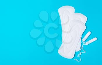 Pad,  tampon on a blue background. The view is flat. Concept of critical days, menstruation