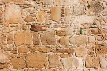 Old, brown, sandy,  wall of a stone house in the open air. Seamless texture background rocks, bricks