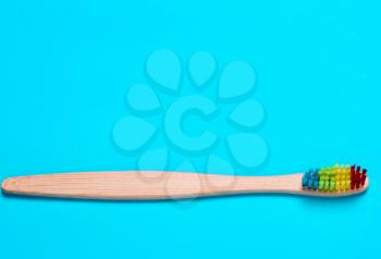 Eco bamboo toothbrush, organic on a blue background of colored bristles.  view i flat, from above. Concept of protection of nature, the environment.