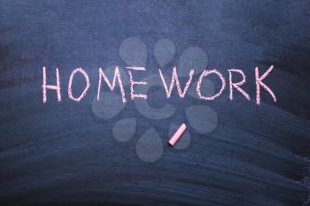 The word homework is written in chalk on a blackboard.
