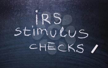 Irs stimulus checks is written in chalk on a blackboard.