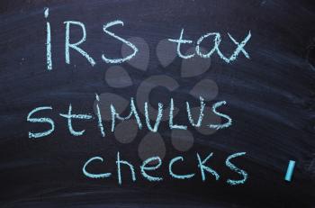 Irs tax stimulus checks is written in chalk on a blackboard.