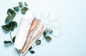 Paper cups, wooden fork, spoon, knife, tube, on a blue background. The concept of recycling, ecology, planet conservation, zero waste