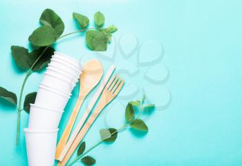 Eco dishes. Paper cups, wooden fork, spoon, knife, tube, on a blue background. The concept of recycling, ecology, planet conservation, zero waste