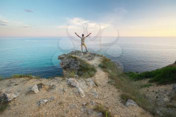 Man stands on the edge of the abyss and enjoy the sea. Man relax on nature.