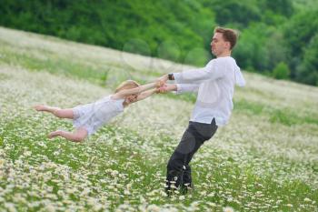 Happy father play with daughter in big camomile mountain meadow. Emotional, love and care scene.