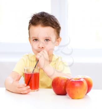 Little boy is drinking apple juice using straw
