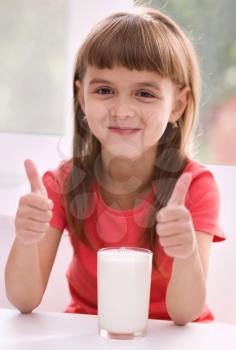 Cute cheerful little girl with a glass of milk