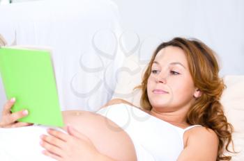 Happy pregnant woman with book