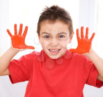 Portrait of a cute boy showing her hands painted in bright colors