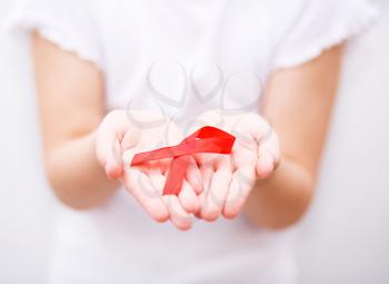 Healthcare and medicine concept - girl hands holding red breast cancer awareness ribbon