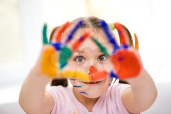 Portrait of a cute cheerful girl showing her hands painted in bright colors