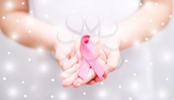 healthcare and medicine concept - girl hands holding pink breast cancer awareness ribbon, over snowy background