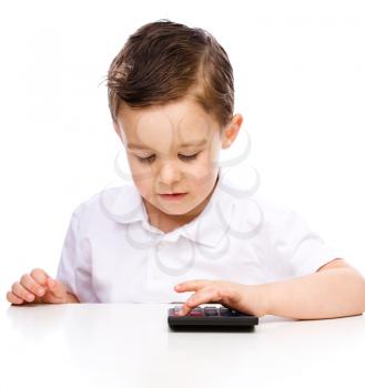 Cute boy is using calculator, isolated over white