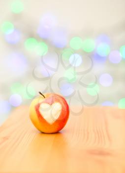 red apple in the form of heart on a wooden background