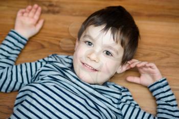 Portrait of happy joyful laughing beautiful little boy on woden background