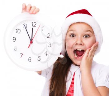 Christmas, winter, time and people concept - girl in santa helper hat with clock, isolated over white