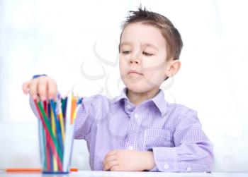 Little boy is holding bunch of color pencils