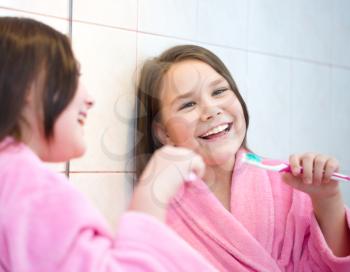 Cute happy girl brushes her teeth in the bathroom