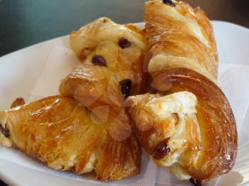 Sweet pastries, flaky croissants with Golden raisins on a white plate