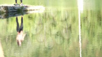 Shot of lake scenic in summer. Blurred nature unfocused background. Lake and forest. People with fishing rods.