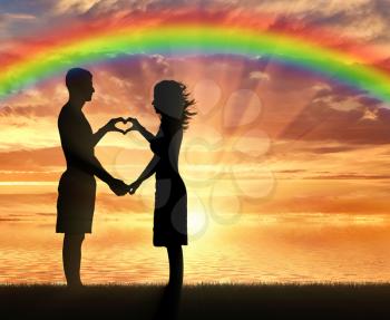 Love and happiness. Young couple showing hands heart symbol on the beach and the rainbow