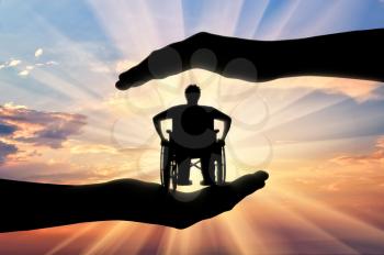 Disabled person in wheelchair in hands on sunset background. Concept protection of disabled persons