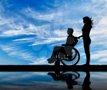 Concept of disability and disease. Silhouette of disabled person with a guardian against the sky and reflection in water
