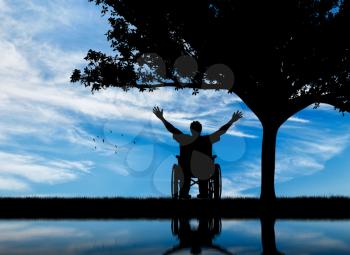 Concept of disability and disease. Silhouette happy invalid under the branches of a tree and reflection in water