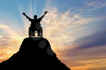 Concept of disability and disease. Silhouette happy disabled person in a wheelchair on the mountain