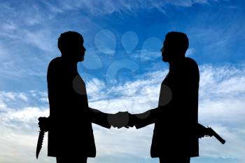  Concept of business betrayal. Silhouette of two businessmen shaking hands and keep arms behind his back weapon