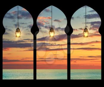 Silhouette arches inside the building of the mosque and the burning lights on the background of sea sunset