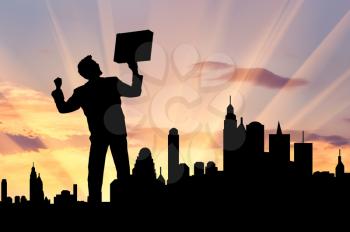 Business success concept. Silhouette of a happy businessman with a briefcase in his hands against the evening city