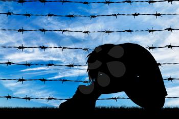 Concept of refugee. Silhouette Despair refugee woman near the fence of barbed wire