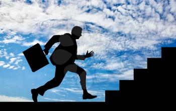 Business concept. Silhouette of running businessman with briefcase in hand in front of the stairs