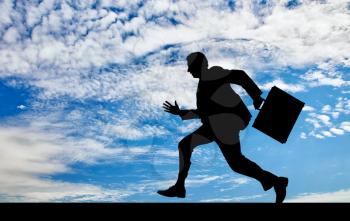 Business concept. Silhouette of running businessman with briefcase in hand against a beautiful sky