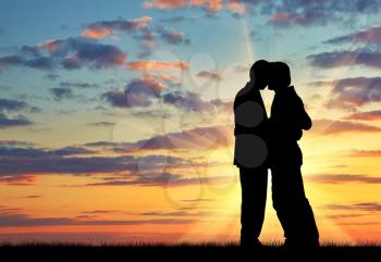 Silhouette of two gay men kissing at sunset