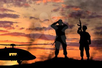 Silhouette of a soldiers and helicopter at sunset