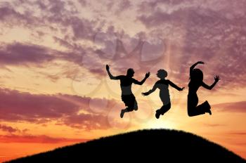 Concept of emotion. Silhouette of a happy group of people jumping at sunset