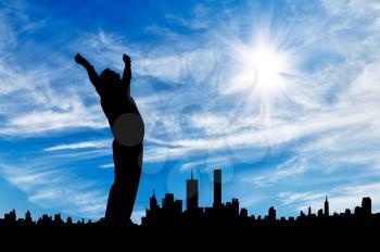Business success concept. Silhouette of a businessman with his hands up against the backdrop of the city on a sunny day