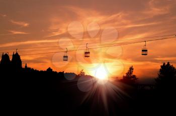 Concept of tourism and travel. Cable car on a background of a fiery sunset