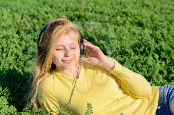 Concept of music. Young woman with headphones listening to music on meadow
